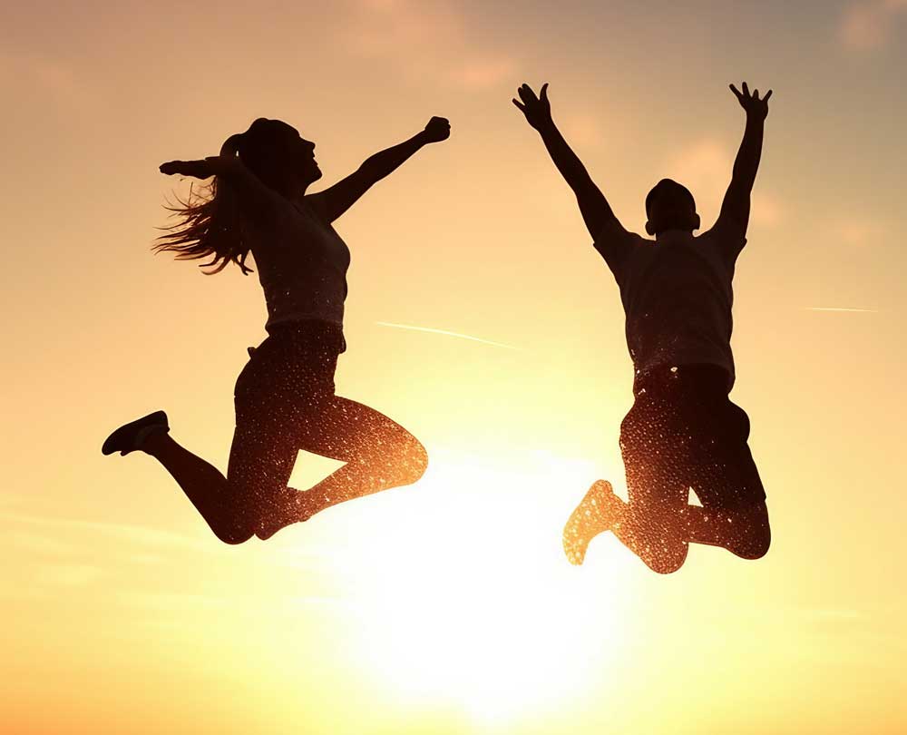 Ein Mann und eine Frau Springen im Sonnenuntergang in die Luft