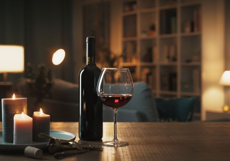 Schlaf und Ernährung: Glas Wein mit Kerzen und Lampen am Abend