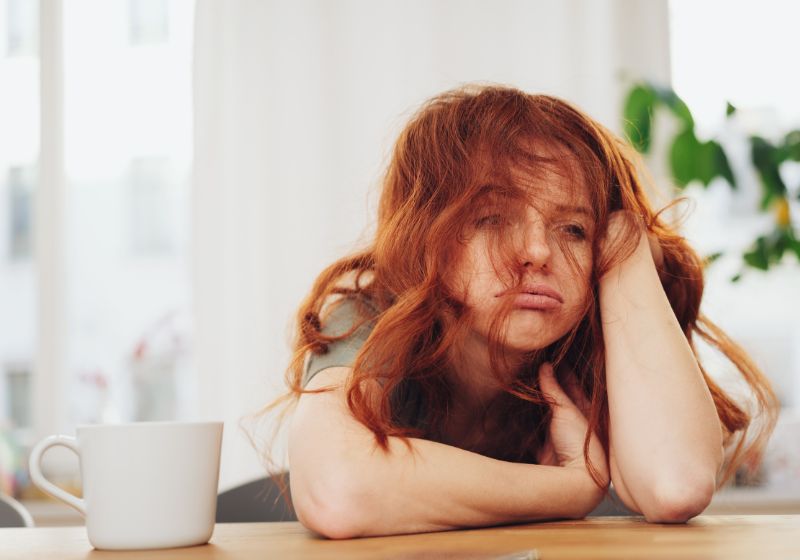 rothaarige frau müde neben einer tasse